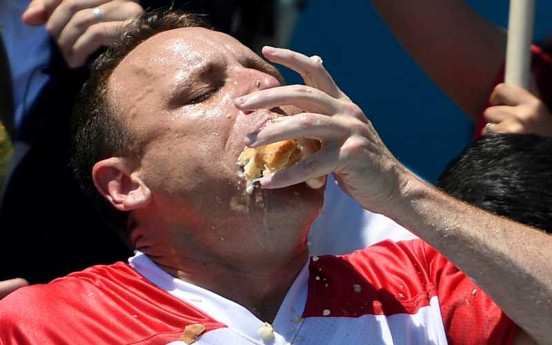 Joey Chestnut shoving a hot dog into his mouth