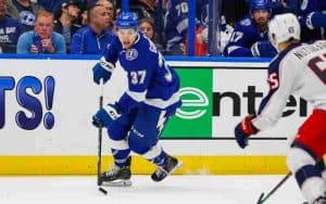 Tampa Bay Lightning player skating with the puck toward a Columbus Blue Jacket player