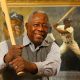 mlb home run king hank aaron posing with a bat in front of his portrait