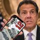 Governor Cuomo holding a smartphone with a mobile sportsbook app pulled up