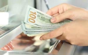 a woman withdrawing cash from a sportbook window