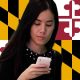 a woman betting on sports on her smartphone in front of the Maryland state flag