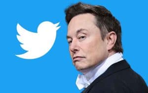 Elon Musk looking at the camera in front of a Twitter logo