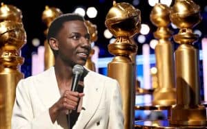 2023 Golden Globes host Jerrod Carmichael in front of several oversized awards