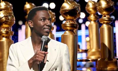 2023 Golden Globes host Jerrod Carmichael in front of several oversized awards