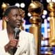 2023 Golden Globes host Jerrod Carmichael in front of several oversized awards