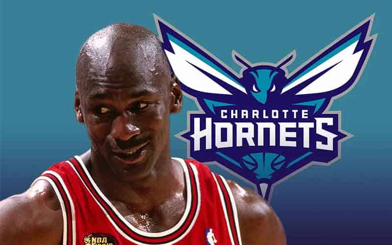 Michael Jordan in front of a Charlotte Hornets logo