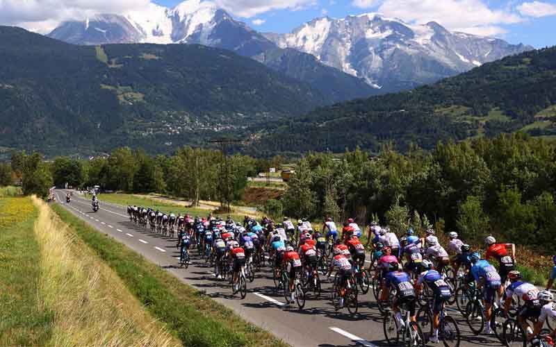 2023 Tour de France competitors racing toward a mountain scape