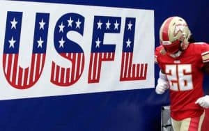 A Birmingham Stallions player running onto the field in front of a USFL banner