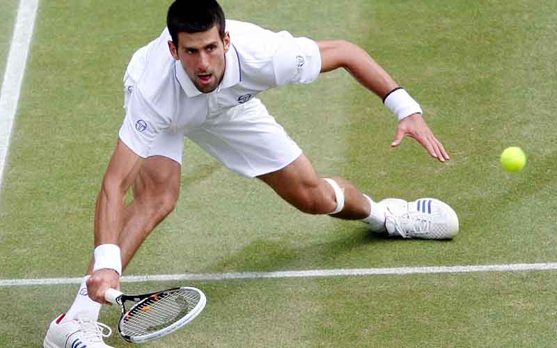 Novak Djokovic melakukan peregangan untuk mendapatkan bola di Wimbledon 2023