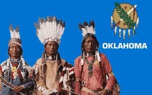 Oklahoma Native American Tribe members in front of an OK state flag