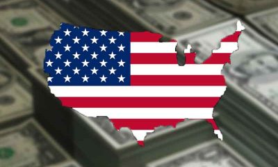 an American flag in the shape of the United States in front of stacks of money