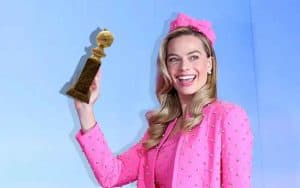 Margot Robbie as Barbie holding a Golden Globe