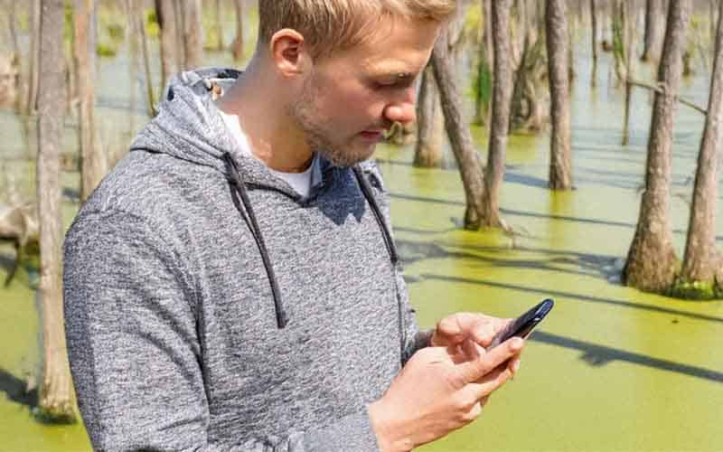 a guy betting on sports on his mobile phone in the swamps of MS