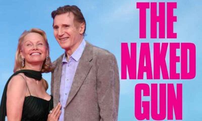 Pamela Anderson and Liam Neeson standing next to a logo for The Naked Gun