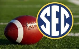 an SEC logo over a football resting on a field