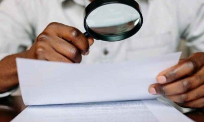 A man using a magifying glass to read sportsbook playthrough conditions