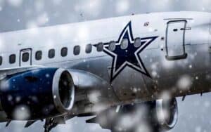 a Dallas Cowboys airplane flying in the snow