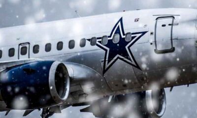a Dallas Cowboys airplane flying in the snow