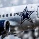a Dallas Cowboys airplane flying in the snow