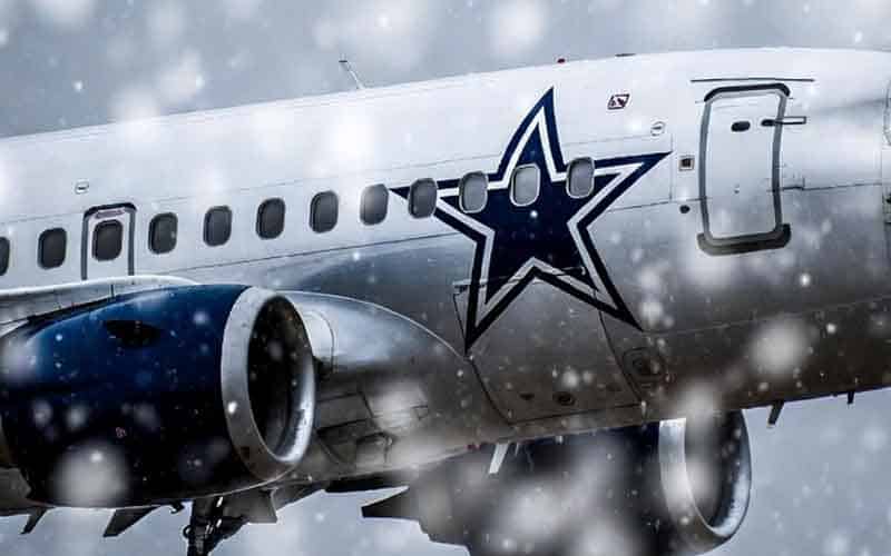 a Dallas Cowboys airplane flying in the snow