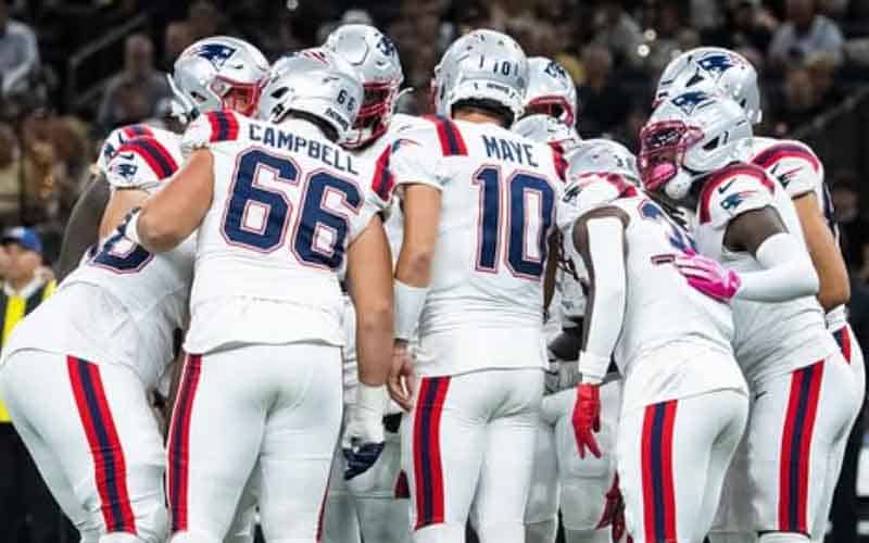 A New England Patriots huddle led by Drake Maye
