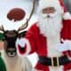 Santa throwing a football to an elf while a reindeer watches