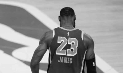 a black and white image of LeBron James walking onto an NBA court