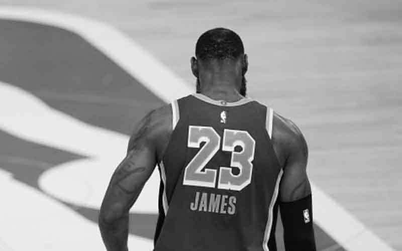 a black and white image of LeBron James walking onto an NBA court