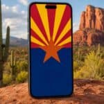 an image of a smartphone with an Arizona flag on the display, positioned in front of the AZ desert