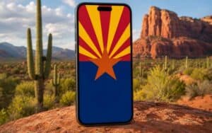 an image of a smartphone with an Arizona flag on the display, positioned in front of the AZ desert