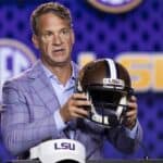 Lane Kiffin at an LSU press conference holding up a helmet