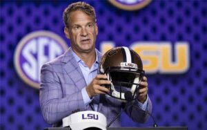 Lane Kiffin at an LSU press conference holding up a helmet