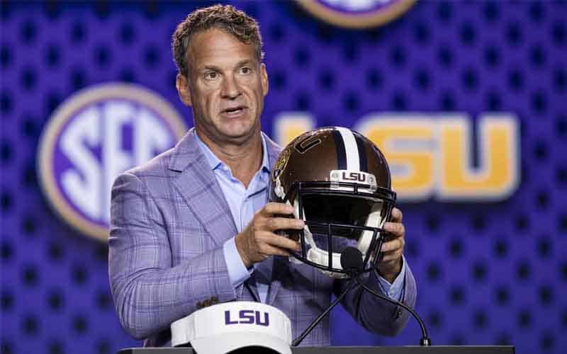 Lane Kiffin at an LSU press conference holding up a helmet